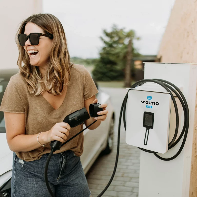 Instalación en pared del Cargador Woltio Pro y una persona cargando su coche eléctrico - Plan MOVES III 2025